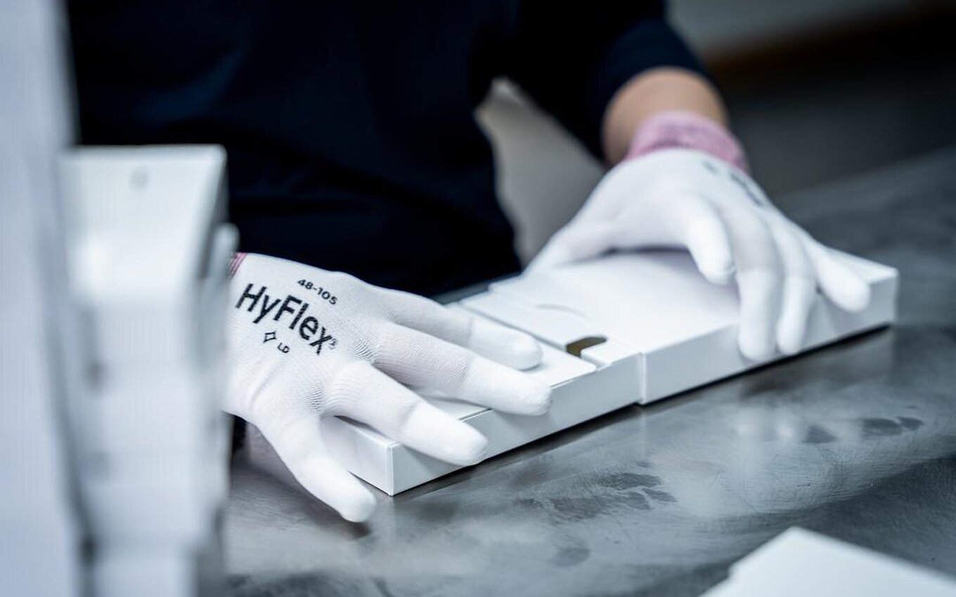 Handarbeit im PrePackaging Service von Faller Packaging – Mitarbeiter faltet pharmazeutische Verpackungen mit höchster Präzision.