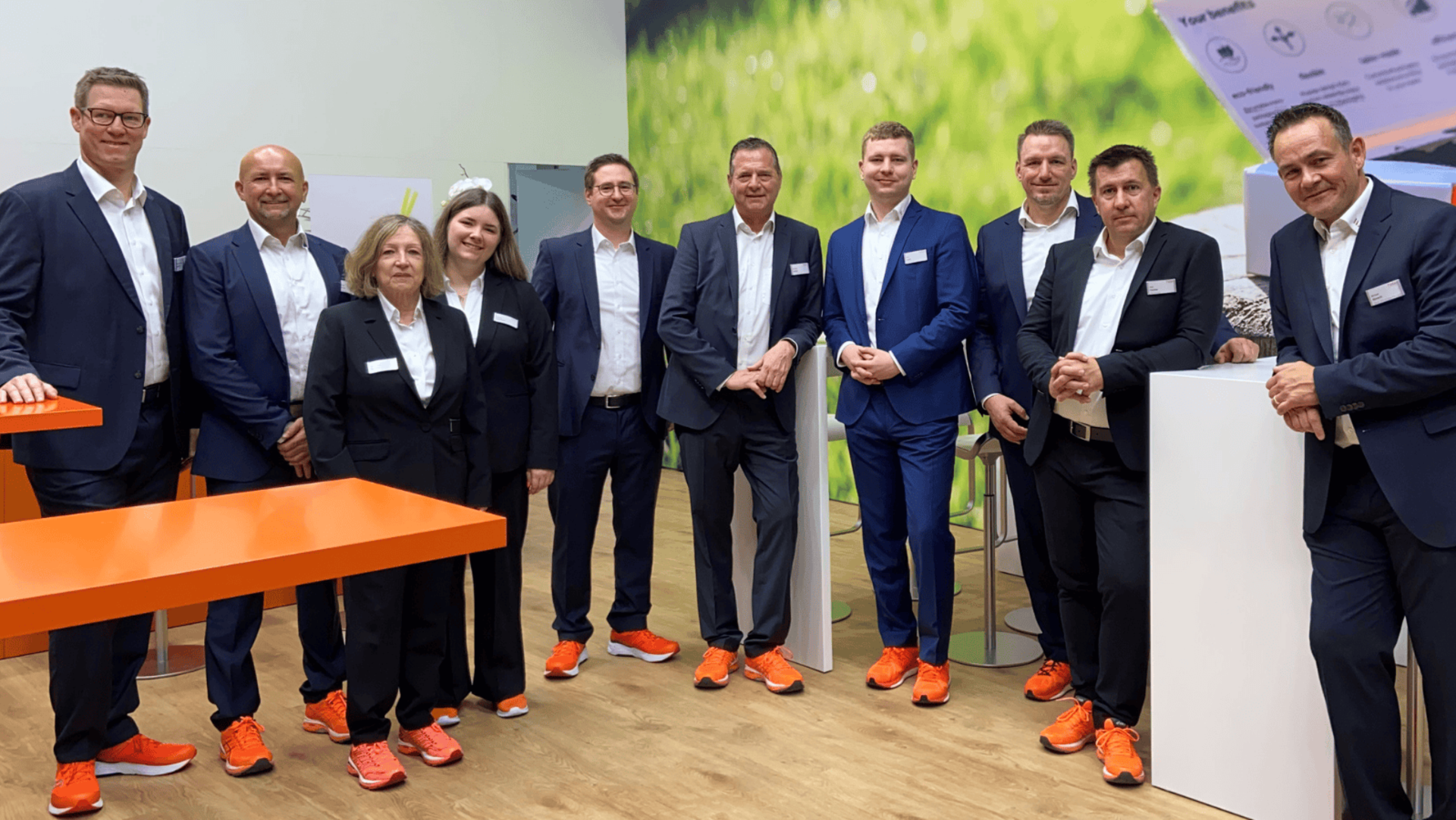 Treffen wir uns auf der CPhI 2025 in Frankfurt? Halle 8 | Stand 8.0M34 Team von Faller Packaging auf der CPhI in Frankfurt in Halle 8, Stand 8.0M34. Die Mitarbeiterinnen und Mitarbeiter tragen elegante Businesskleidung mit markanten orangefarbenen Sneakern und begrüßen Besucher am modernen Messestand. Treffen Sie unsere Verpackungsexperten und erfahren Sie mehr über innovative pharmazeutische Verpackungslösungen.