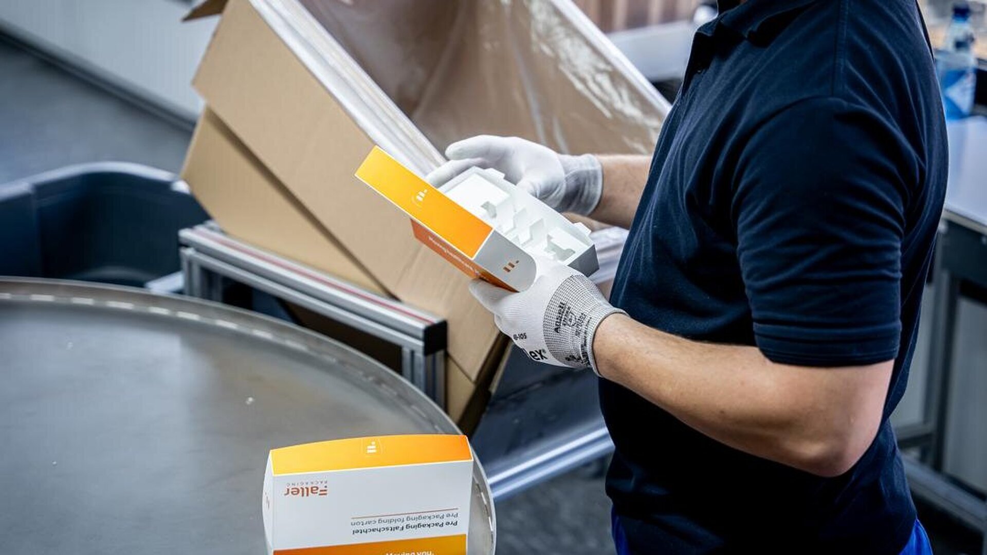 Schneller am Markt - mit unserem PrePackaging Service Ein Mitarbeiter von Faller Packaging prüft im Bereich PrePackaging eine pharmazeutische Faltschachtel mit integriertem Inlay während der Produktion. Das Bild zeigt Präzision, Qualität und Innovationskraft in der Sekundärverpackung für die Healthcare-Branche.
